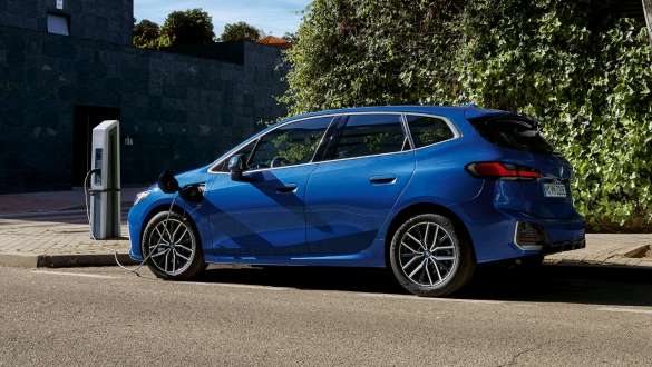 Plug-in hybridní BMW řady 2 Active Tourer 230e U06 2021 parkující u nabíjecí stanice Plug-in hybridní BMW řady 2 Active Tourer 230e U06 2021 v metalické barvě M Portimao Blue (modrá) pohled z boku parkující u nabíjecí stanice