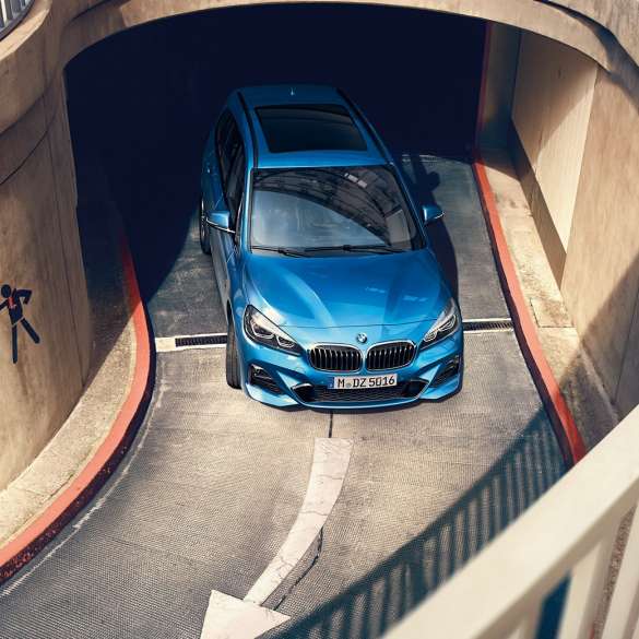 BMW řady 2 Gran Tourer při jízdě parkovacím domem BMW řady 2 Gran Tourer F46 v metalické 2018 barvě Misano Blue (modrá) pohled z ptačí perspektivy při jízdě parkovacím domem