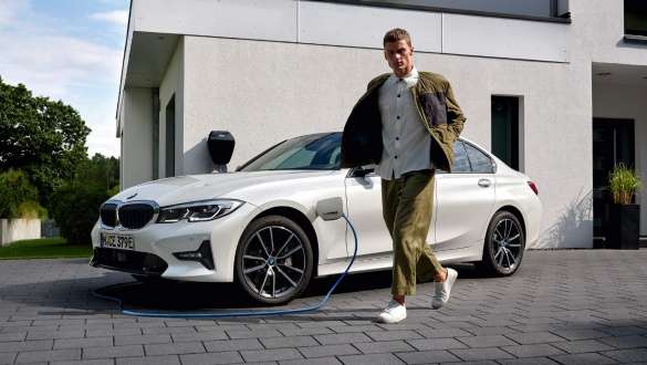 Plug-in hybridní BMW řady 3 Sedan 2021 G20 tříčtvrteční pohled zepředu při nabíjení Plug-in hybridní BMW řady 3 Sedan 2021 G20 tříčtvrteční pohled zepředu při nabíjení s modelem