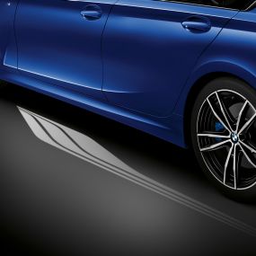 BMW řady 3 Sedan, Světelný koberec. Detail ze strany do interiéru otevřenými dveřmi řidiče se světelným kobercem rozsvíceným vedle vozu.