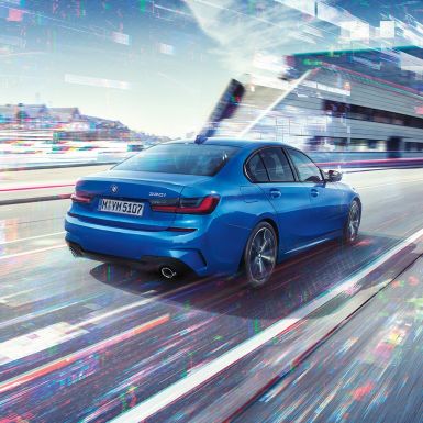 BMW řady 3 Sedan, boční pohled zezadu Zadní tříčtvrteční pohled na BMW řady 3 Sedan ve dne před městskou zástavbou.