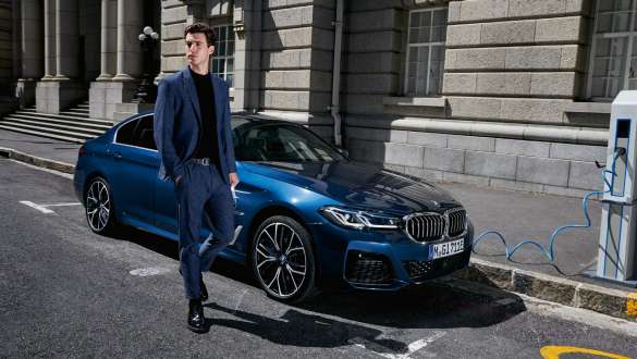 Plug-in hybridní BMW řady 5 Sedan 2021 G30 tříčtvrteční pohled zepředu při nabíjení Plug-in hybridní BMW řady 5 Sedan 2021 G30 tříčtvrteční pohled zepředu při nabíjení s modelem