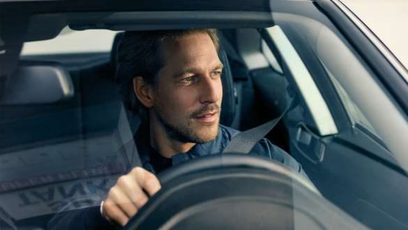 Muž řídí BMW Muž řídí BMW a dívá se vpřed přes čelní sklo