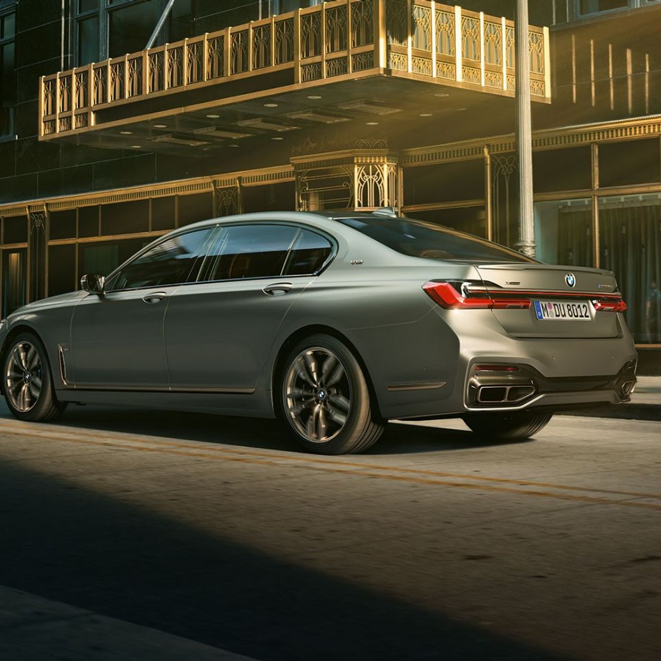 BMW M760Li xDrive s motorem V12 BMW M760Li xDrive v bočním zadním pohledu stojící před mrakodrapy městské zástavby