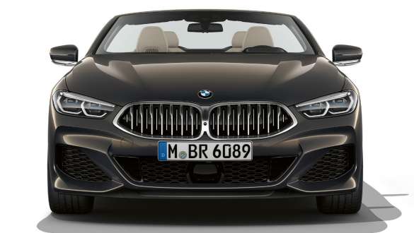 BMW M850i xDrive Cabrio, přední část. BMW M850i xDrive Cabrio v šedé metalíze Dravit Grey se staženou střechou, přední maska chladiče ve tvaru ledvinek v šedé Galvanic Cerium Grey.
