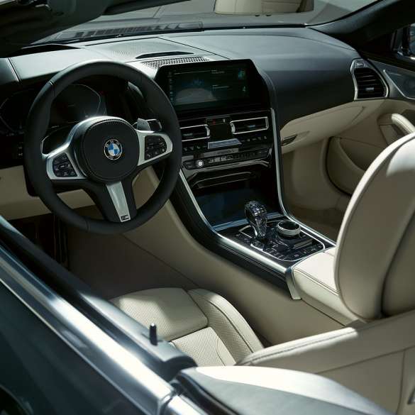 BMW M850i xDrive Cabrio, kokpit. BMW M850i xDrive Cabrio v šedé barvě Dravit Grey se staženou střechou, kokpit s M koženým volantem.