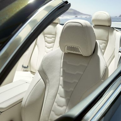 BMW M850i xDrive Cabrio, multifunkční sedadla řidiče a pasažéra vpředu. BMW M850i xDrive Cabrio v šedé metalíze Dravit Grey se staženou střechou, interiér s multifunkčními sedadly čalouněnými bílou kůží BMW Individual Merino Ivory White.