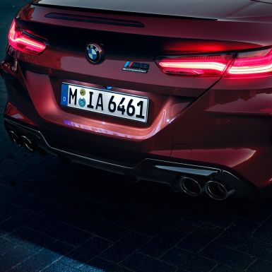 BMW M8 Competition Cabrio, detailní pohled na záď. BMW M8 Competition Cabrio v červené metalíze Motegi Red, detailní pohled na zadní světla a znak M8 Competition.