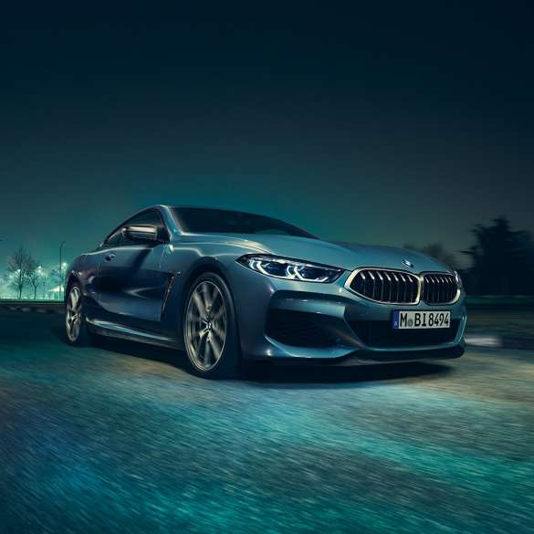 BMW M850i xDrive Coupé, tříčtvrteční pohled zleva za jízdy. BMW M850i xDrive Coupé v metalické barvě Barcelona Blue, tříčtvrteční pohled zleva, za jízdy v noci.