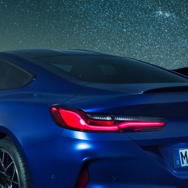 M zadní spoiler BMW M8 Competition Coupé v metalické barvě Marina Bay Blue, noční detail zadní boční části s M zadním spoilerem.