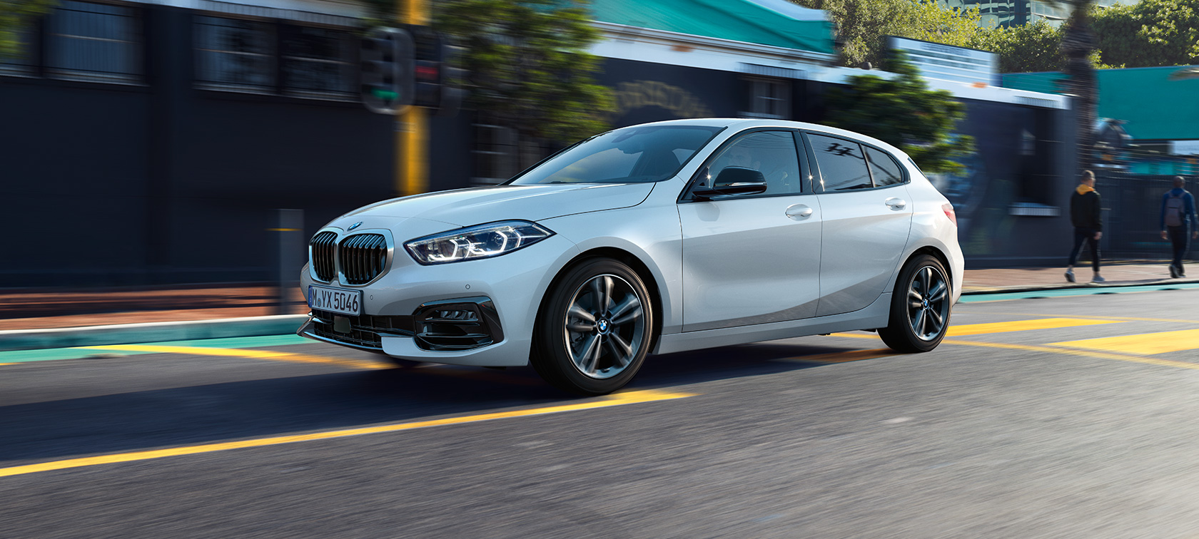 BMW řady 1 Model Sport Line, tříčtvrteční pohled z boku. Tříčtvrteční pohled z boku na jedoucí BMW řady 1 v provedení Model Sport Line v bílé metalické barvě Mineral White.
