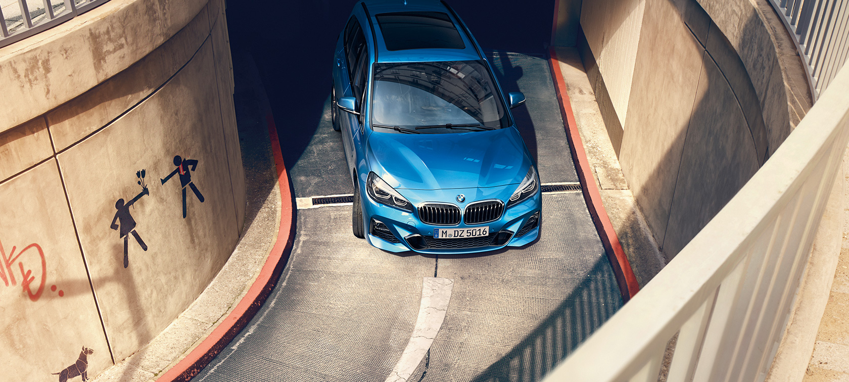 BMW řady 2 Gran Tourer v parkovacím domě BMW řady 2 Gran Tourer F46 v metalické barvě Misano Blue (modrá) pohled z ptačí perspektivy při jízdě parkovacím domem