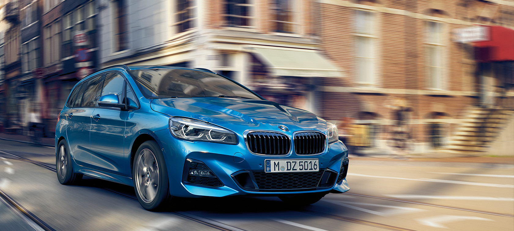 BMW řady 2 Gran Tourer při jízdě na silnici BMW řady 2 Gran Tourer F46 2018 v metalické barvě Misano Blue (modrá) ze tříčtvrtečního pohledu zepředu za jízdy