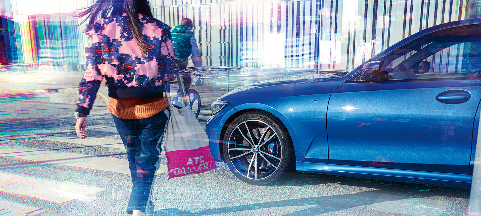 BMW řady 3 Sedan, tříčtvrteční pohled z boku Tříčtvrteční pohled z boku na BMWW řady 3 Sedan s cestujícími na asfaltu před městskou zástavbou.