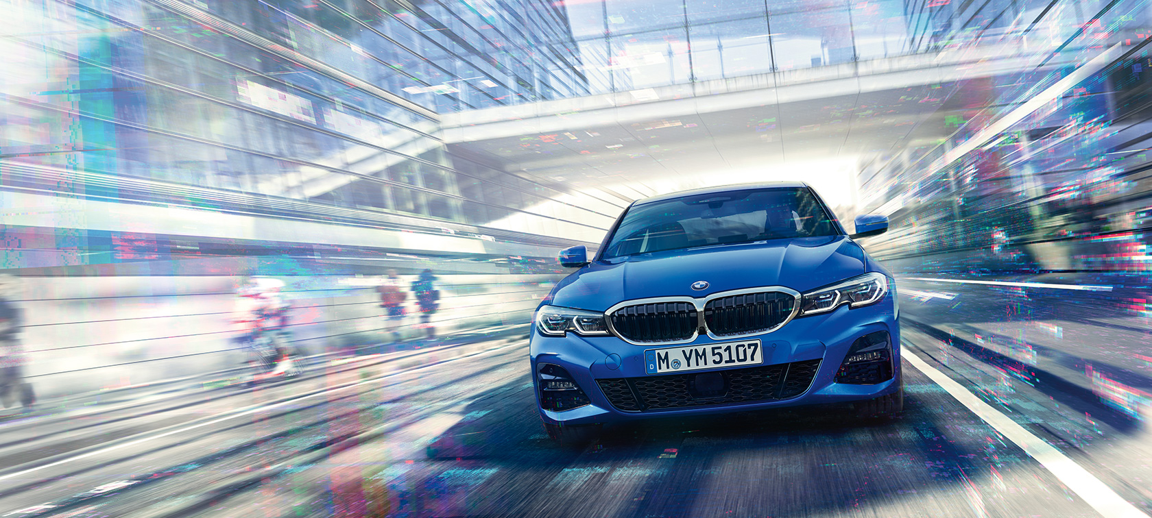 BMW řady 3 Sedan, pohled zpředu. Pohled zpředu na BMW řady 3 Sedan jedoucí pod skleněnou budovou.