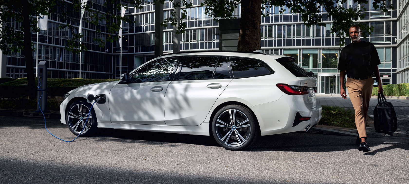 Plug-in hybridní BMW řady 3 Touring 2021 G21 tříčtvrteční pohled z boku při nabíjení Plug-in hybridní BMW řady 3 Touring 2021 G21 tříčtvrteční pohled z boku při nabíjení s modelem