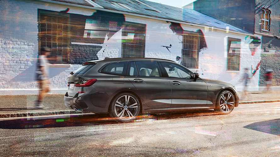 BMW řady 3 Touring (G21) v šedé barvě Dravit Grey, 7/8 jízdní záběr zezadu před budovou BMW řady 3 Touring (G21) v šedé barvě Dravit Grey, 7/8 jízdní záběr zezadu před budovou