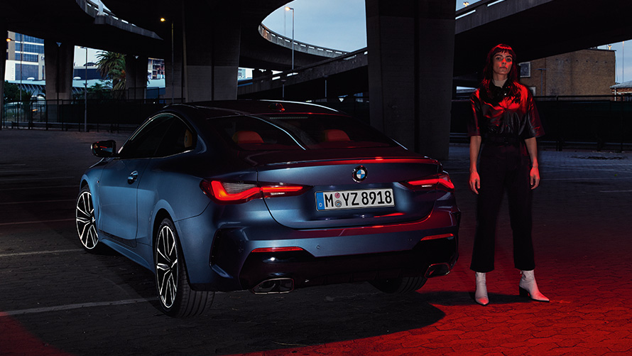 BMW řady 4 Coupé (G22), Artic Race Blue (modrá) pohled na zadní část s osobou BMW řady 4 Coupé (G22), Artic Race Blue (modrá) pohled na zadní část s osobou
