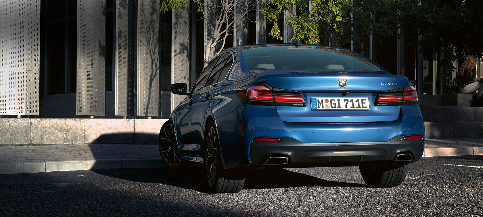 BMW řady 5 Sedan (G30), metalický lak Phytonic Blue (modrá) BMW řady 5 Sedan eDrive (G30) metalický lak Phytonic Blue (modrá), pohled zezadu na zaparkované před budovou