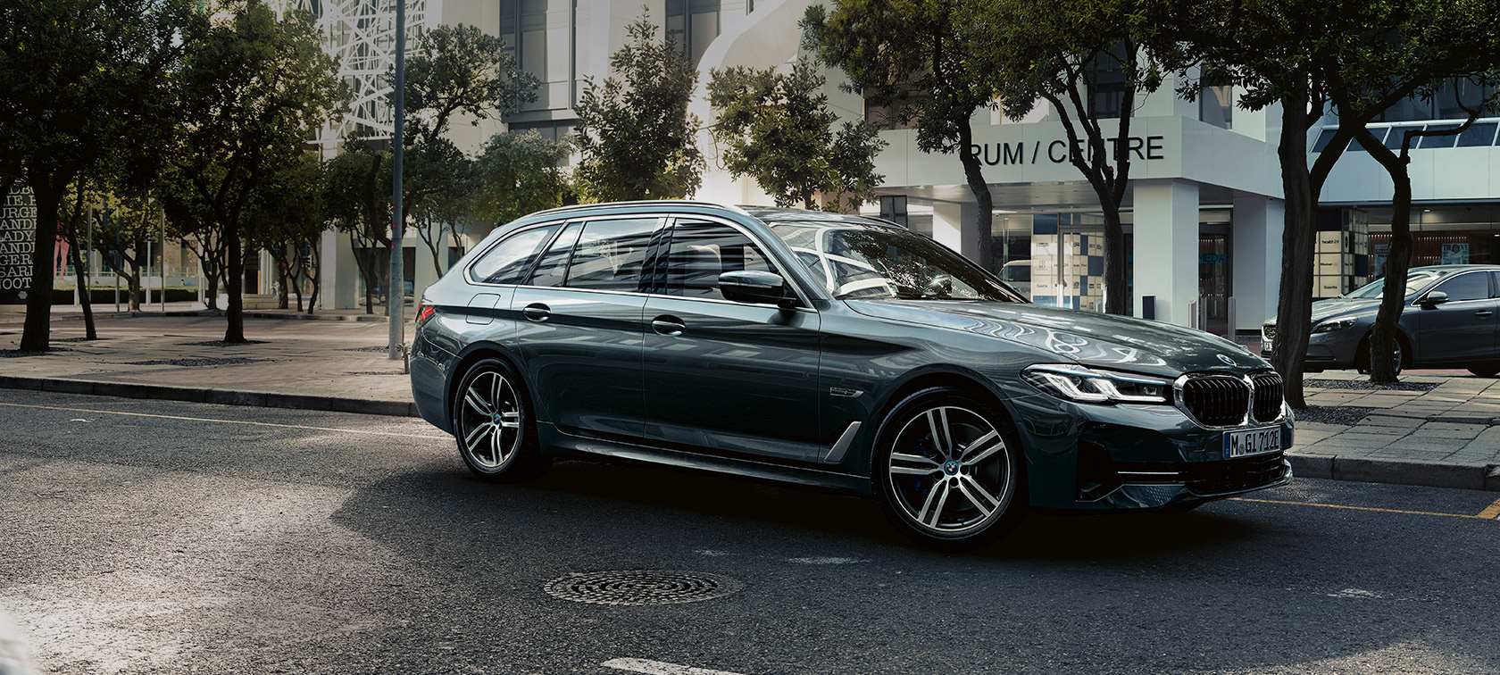 BMW řady 5 Touring G31 Facelift 2020 Sophisto Grey (šedá) 7/8 jízdní záběr zepředu na okraji města