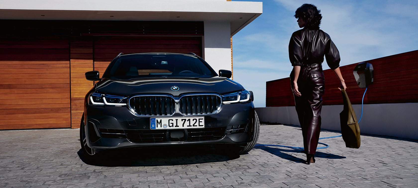 Plug-in hybridní BMW řady 5 Touring 2021 G31 LCI ze tříčtvrtečního pohledu zepředu při nabíjení Plug-in hybridní BMW řady 5 Touring ze tříčtvrtečního pohledu zepředu při nabíjení s modelem