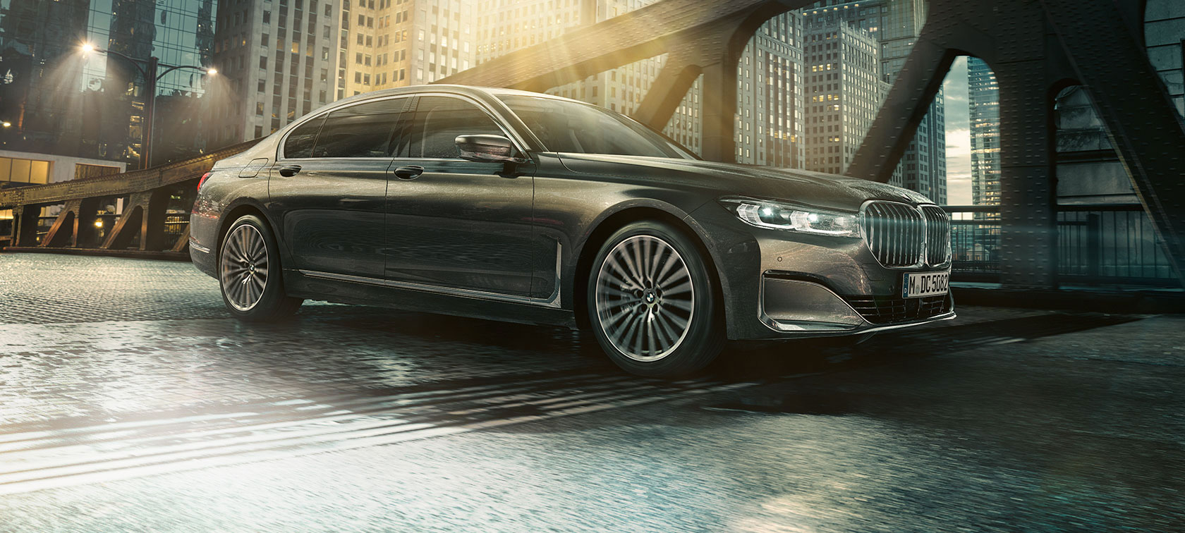 Boční pohled na BMW řady 7 Sedan Boční pohled na BMW řady 7 Sedan s otevřenými dveřmi před osvětleným hotelem