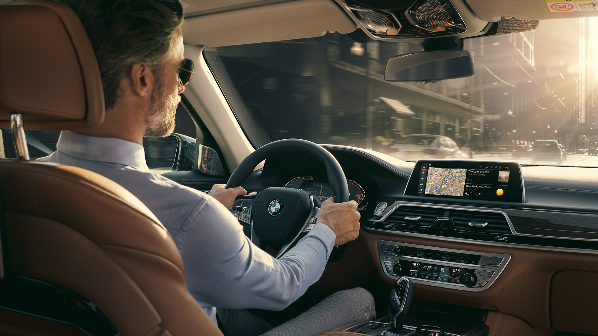 Funkce konektivity BMW řady 7 Sedan BMW řady 7 Sedan: muž sedí v BMW a používá funkce konektivity