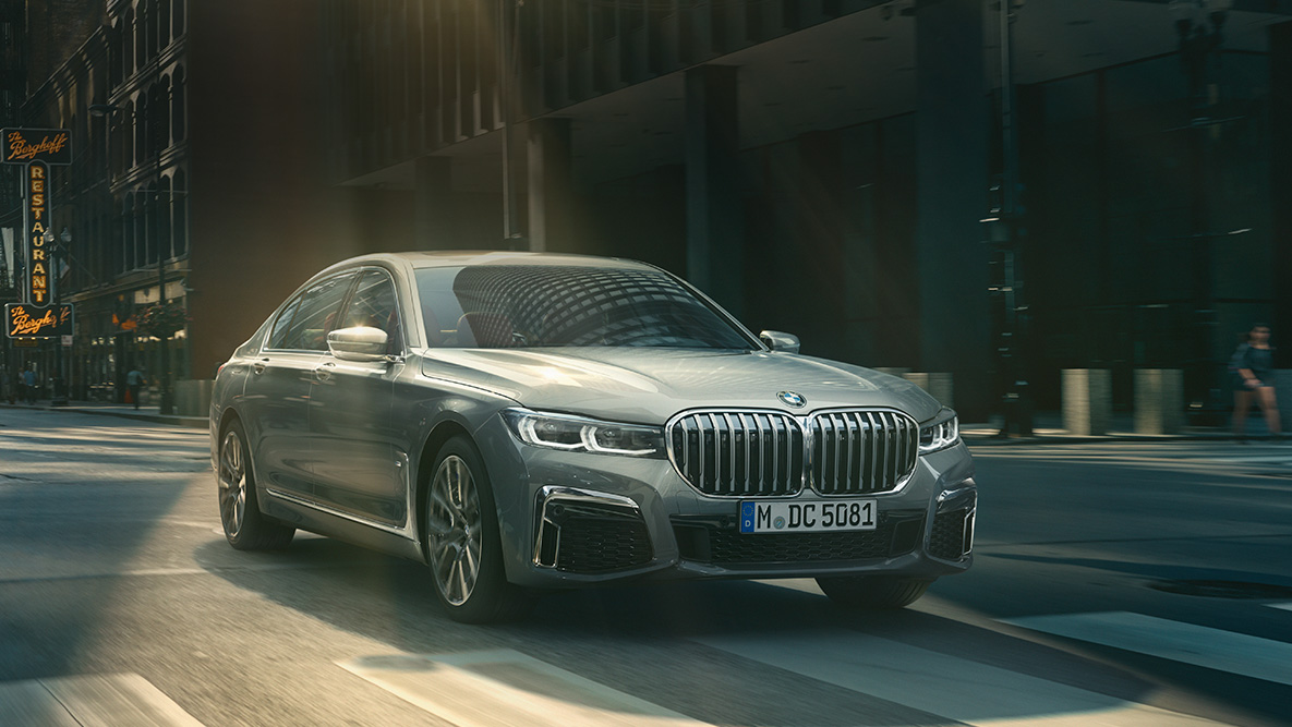 BMW řady 7 Sedan Driving Assistant Professional Driving Assistant Professional: tříčtvrteční pohled zpředu na BMW řady 7 Sedan jedoucí před městskou zástavbou