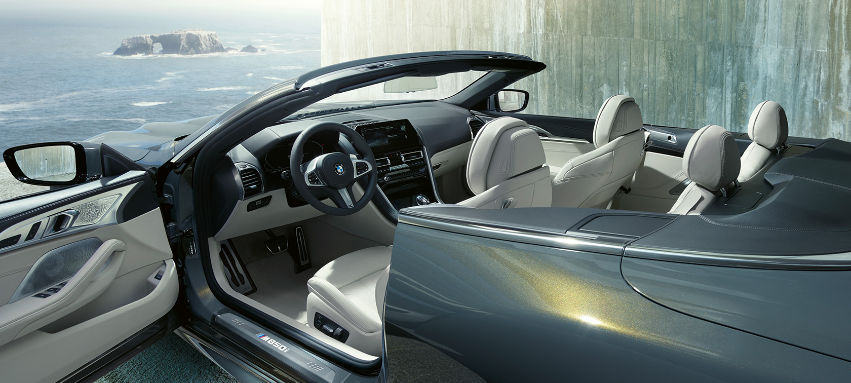 BMW M850i xDrive s metalickým lakem Dravit Grey, boční pohled, plátěná střecha a otevřené dveře. BMW M850i xDrive s metalickým lakem Dravit Grey, boční pohled, plátěná střecha a otevřené dveře.
