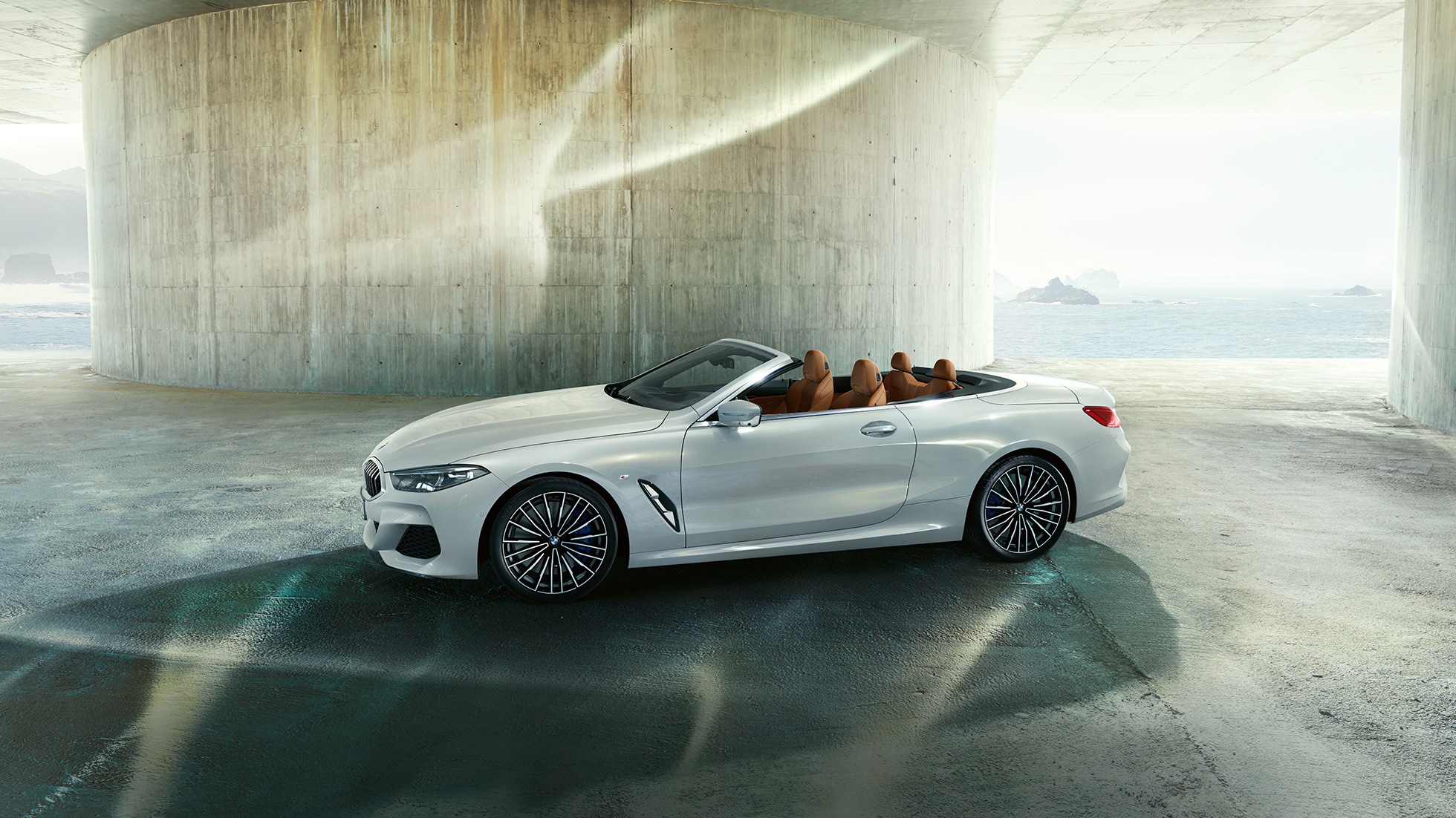 BMW M850i xDrive v metalickém laku Mineral White, boční pohled s otevřenou střechou. BMW M850i xDrive v metalickém laku Mineral White, boční pohled s otevřenou střechou.