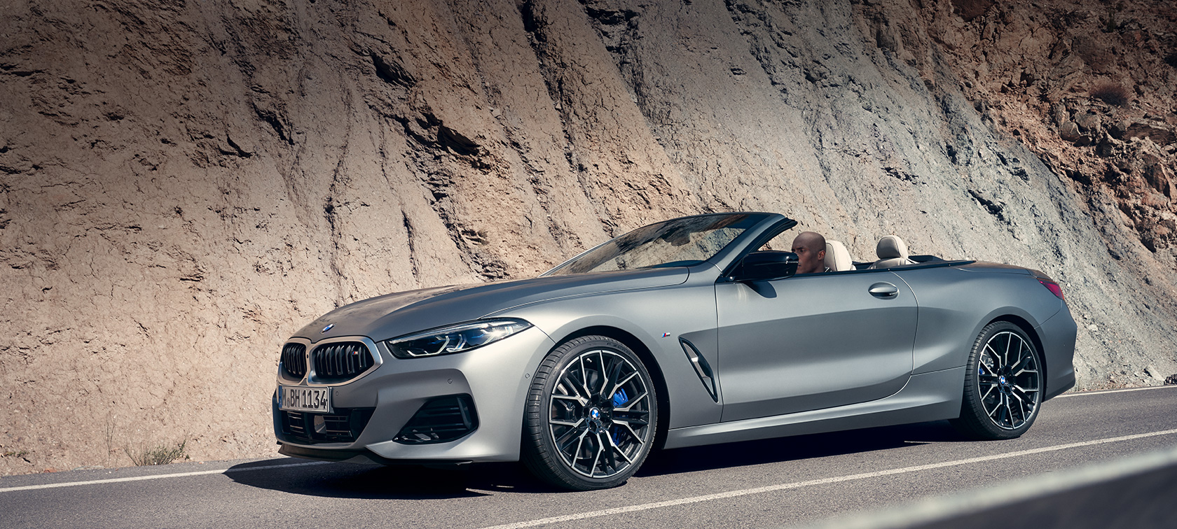 BMW řady 8 Cabrio G14 LCI Facelift 2022 BMW M850i xDrive BMW Individual metalický lak Frozen Pure Grey (šedá) tříčtvrteční pohled zboku před budovou BMW řady 8 Cabrio G14 LCI Facelift 2022 BMW M850i xDrive BMW Individual metalický lak Frozen Pure Grey (šedá) tříčtvrteční pohled z boku před budovou