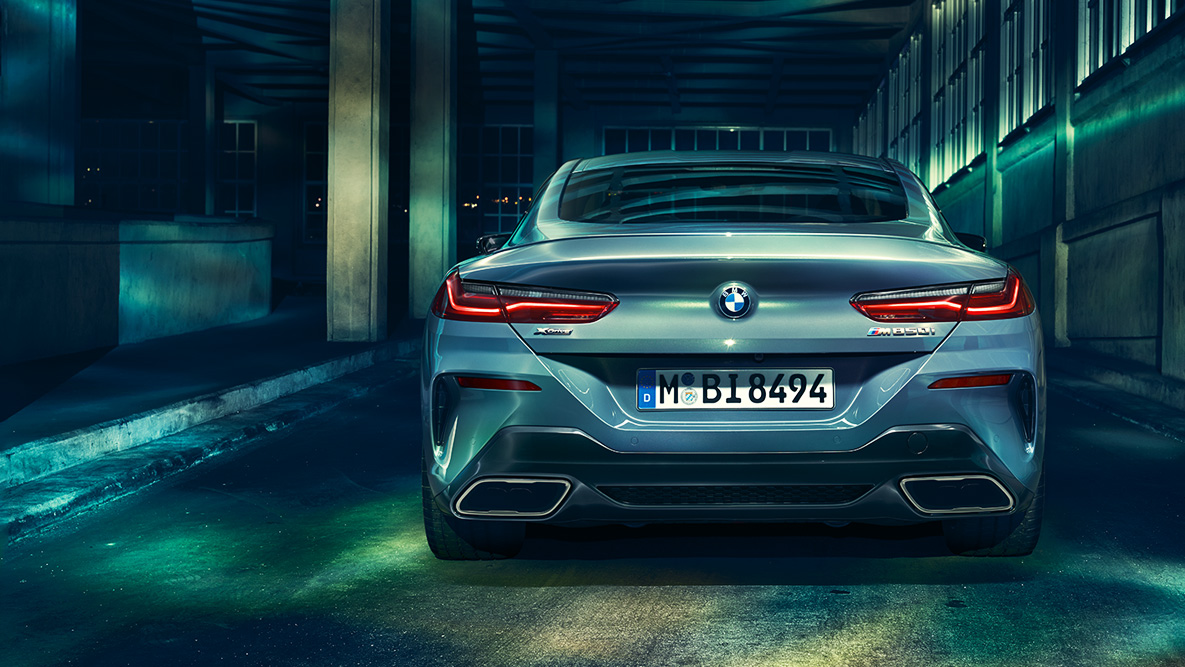 BMW řady 8 Coupé, pohled zezadu. Pohled na BMW řady 8 Coupé zezadu v noci v městském prostředí.