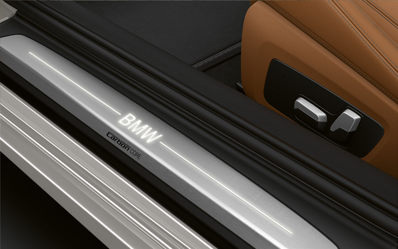 BMW řady 8 Coupé, prahová lišta s logem BMW. Detailní pohled na prahovou lištu BMW řady 8 Coupé s logem BMW.