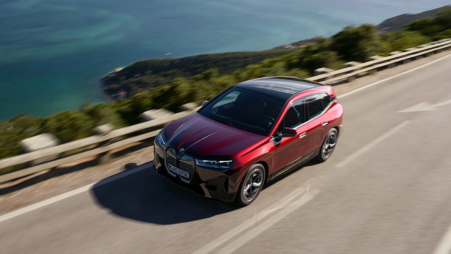 BMW iX i20 elektrické SUV BMW iX xDrive50 jízdní výkony BMW iX i20 2021 elektrické SUV BMW iX xDrive50 Aventurin Red (červená) jedoucí po silnici jízdní výkony