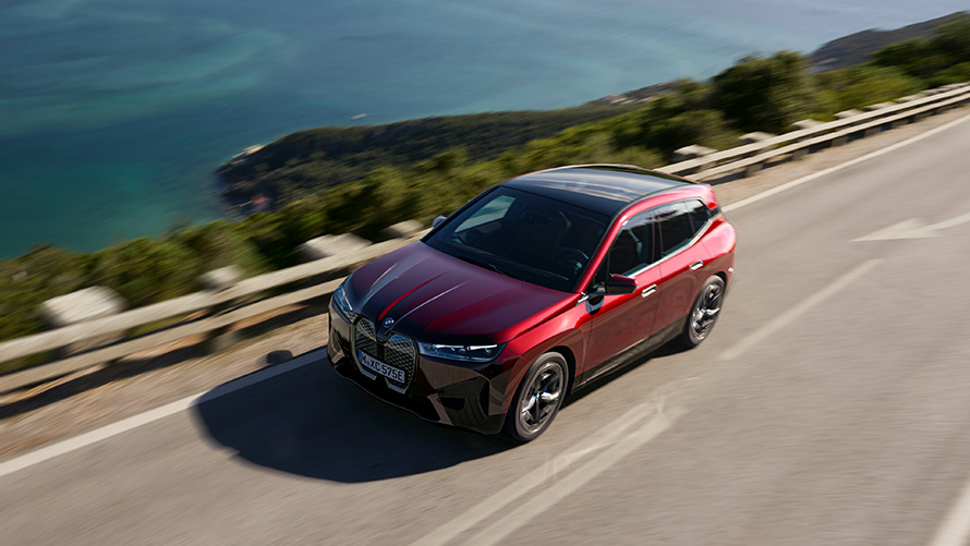 BMW iX i20 elektrické SUV BMW iX xDrive50 jízdní výkony BMW iX i20 2021 elektrické SUV BMW iX xDrive50 Aventurin Red (červená) jedoucí po silnici jízdní výkony
