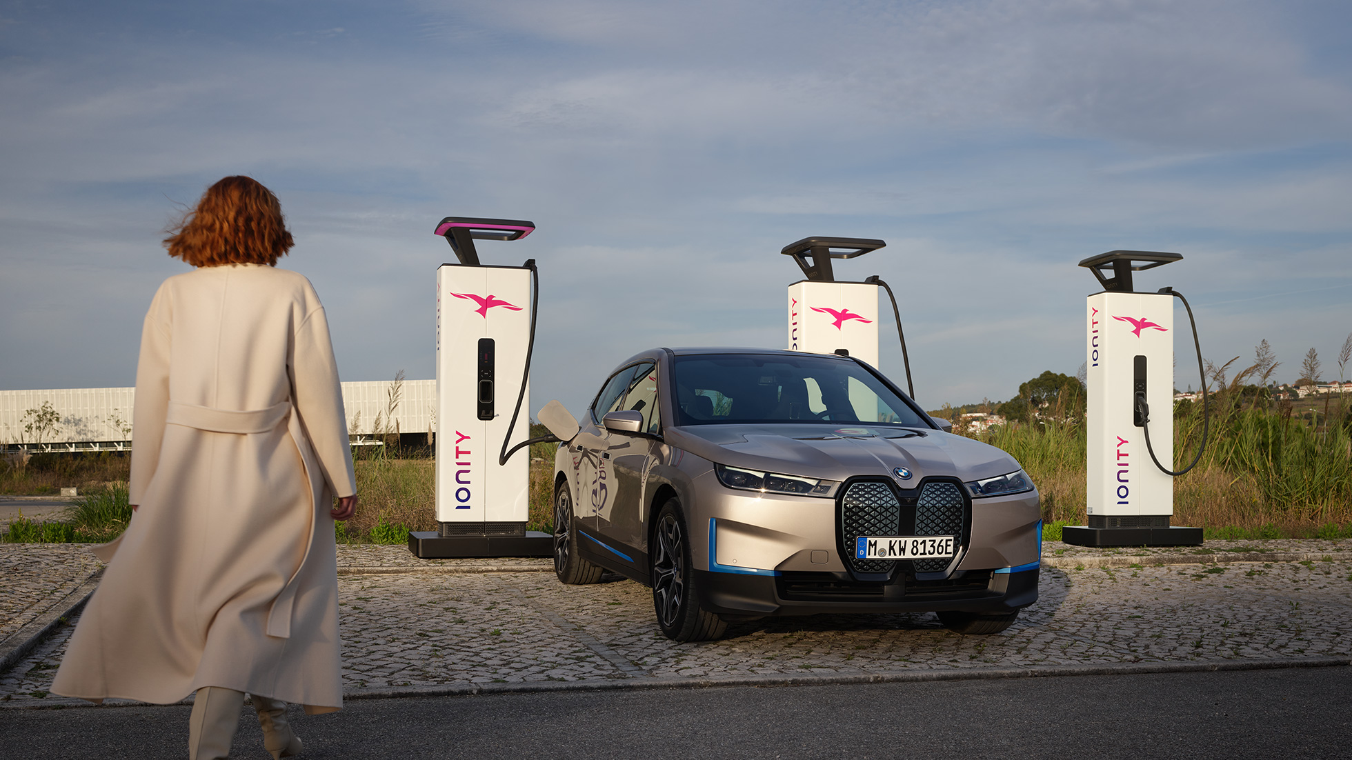 BMW iX tříčtvrteční pohled zepředu u nabíjecí stanice BMW iX Cashmere Silver i20 tříčtvrteční pohled zepředu u nabíjecí stanice