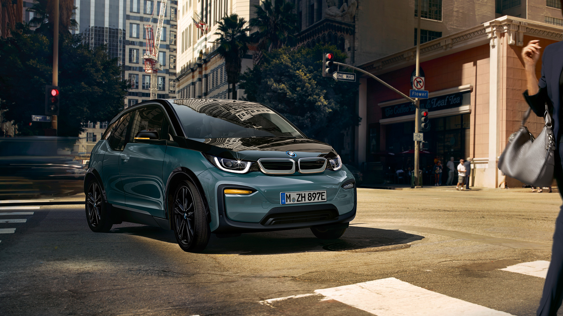 BMW i3 2018 ze tříčtvrtečního pohledu zepředu při jízdě BMW i3 I01 2018 v barvě Jucaro (béžová) s matně šedými kontrastními prvky Frozen Grey ze tříčtvrtečního pohledu zepředu při parkování ve městě