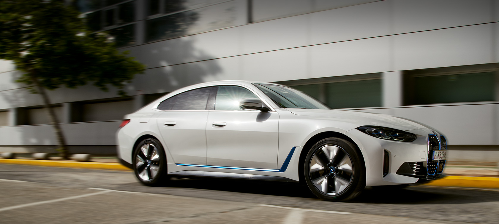 BMW i4 eDrive40 G26 2021 tříčtvrteční pohled zepředu jedoucí před budovou BMW i4 eDrive40 G26 2021 tříčtvrteční pohled zepředu jedoucí před budovou