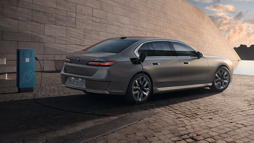 BMW i7 Sedan G70 paket 3/4 pohled zezadu BMW i7 Sedan G70 BMW Individual metalický lak Oxid Grey (šedá) 3/4 pohled z boku u nabíjecí stanice