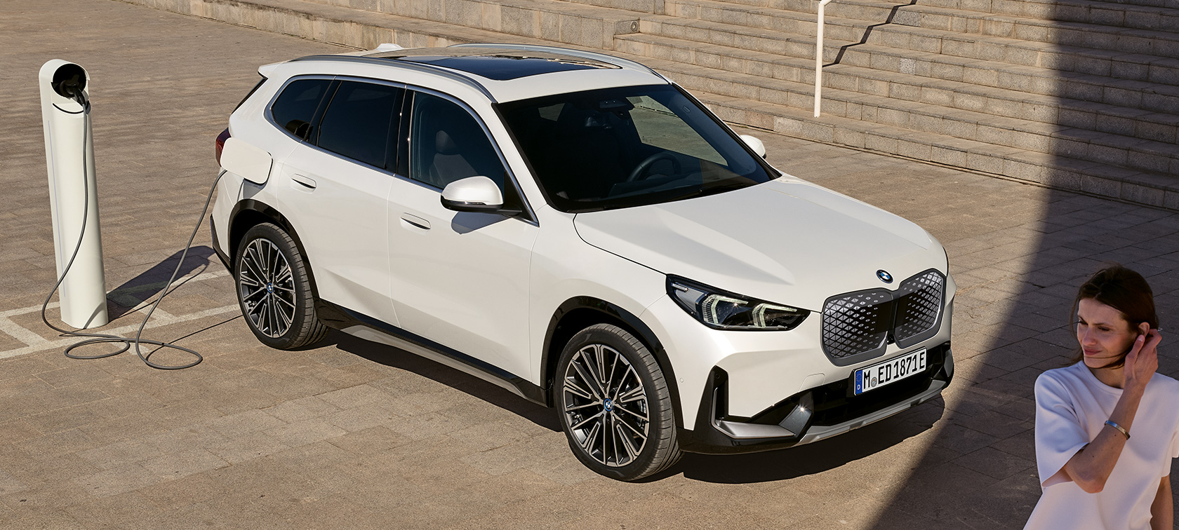 BMW iX1 U11 BEV 2022 pohled z boku nabíjení BMW iX1 U11 BEV 2022 metalický lak Mineral White dvoutřetinový pohled z boku nabíjení