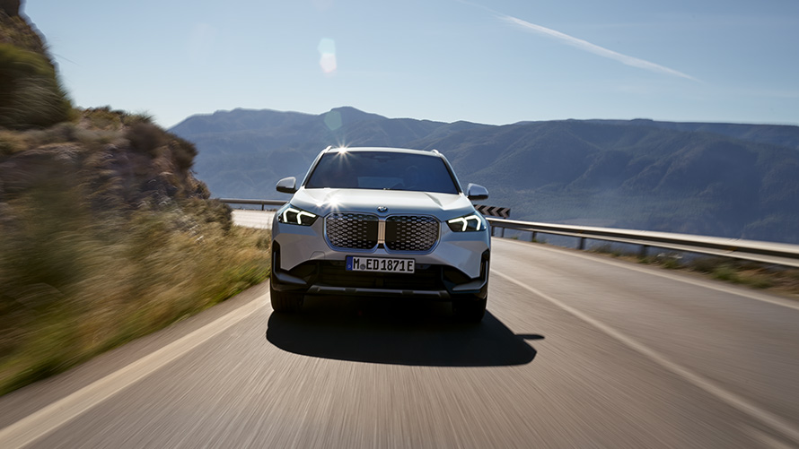 BMW iX1 U11 BEV pohled zepředu BMW iX1 U11 BEV 2022 metalický lak Mineral White pohled zepředu na horské silnici