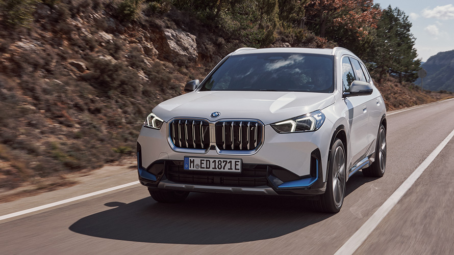 BMW iX1 U11 první generace, jízdní tříčtvrteční záběr zepředu na silnici BMW X modely BMW iX1 U11 první generace, jízdní tříčtvrteční záběr zepředu na silnici
