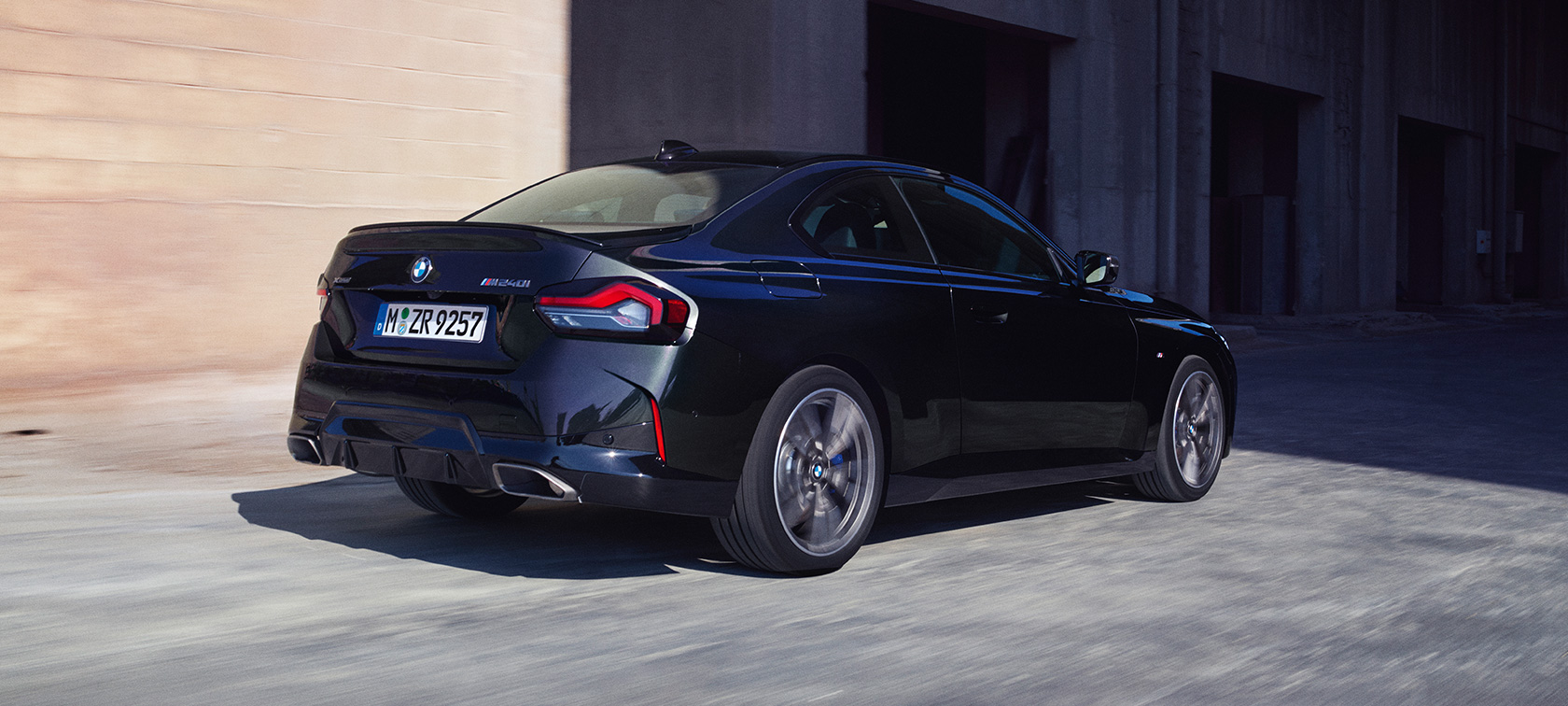 Tříčtvrteční pohled zezadu BMW M240i xDrive Coupé G42 2021 BMW M240i xDrive Coupé G42 2021 metalický lak Black Sapphire (černá) jízdní tříčtvrteční záběr zezadu