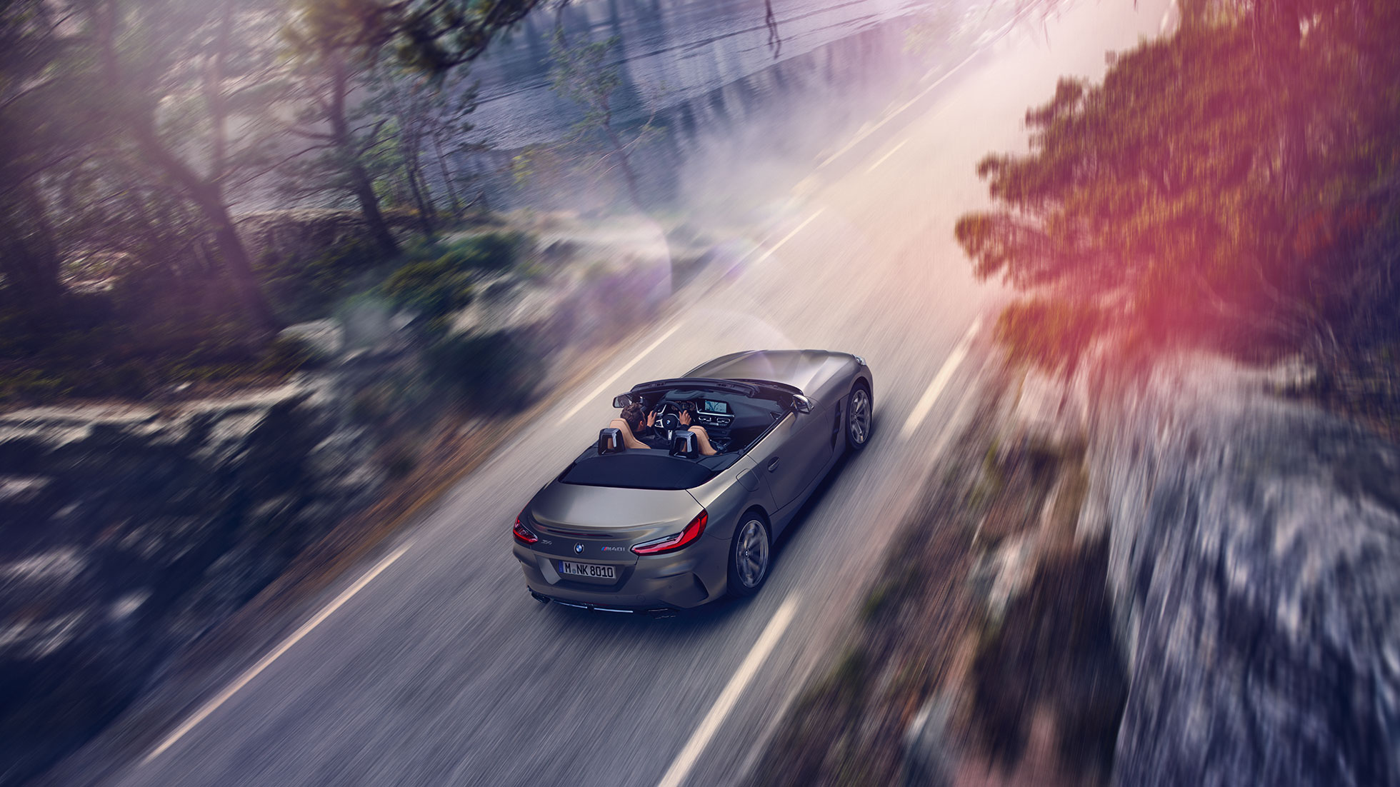 BMW Z4 M40i G29 s otevřenou skládací střechou BMW Z4 M40i Roadster G29 2019 BMW Individual metalický lak Frozen Grey (šedá) jízdní záběr z ptačí perspektivy s otevřenou skládací střechou