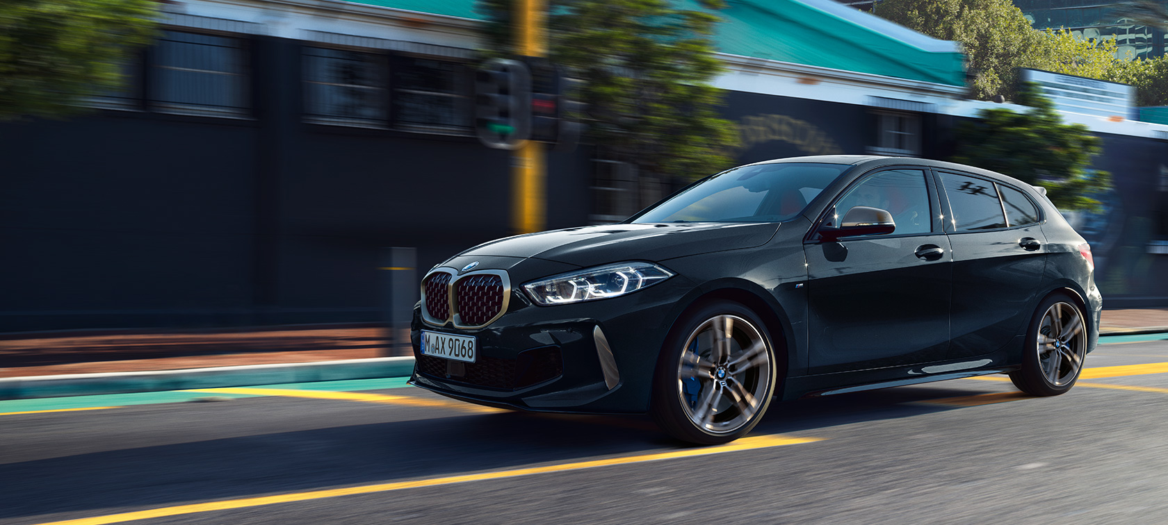 Zcela nové BMW M135i xDrive Zcela nové BMW M135i xDrive v černé metalíze Black Sapphire, tříčtvrteční jízdní záběr z boku.