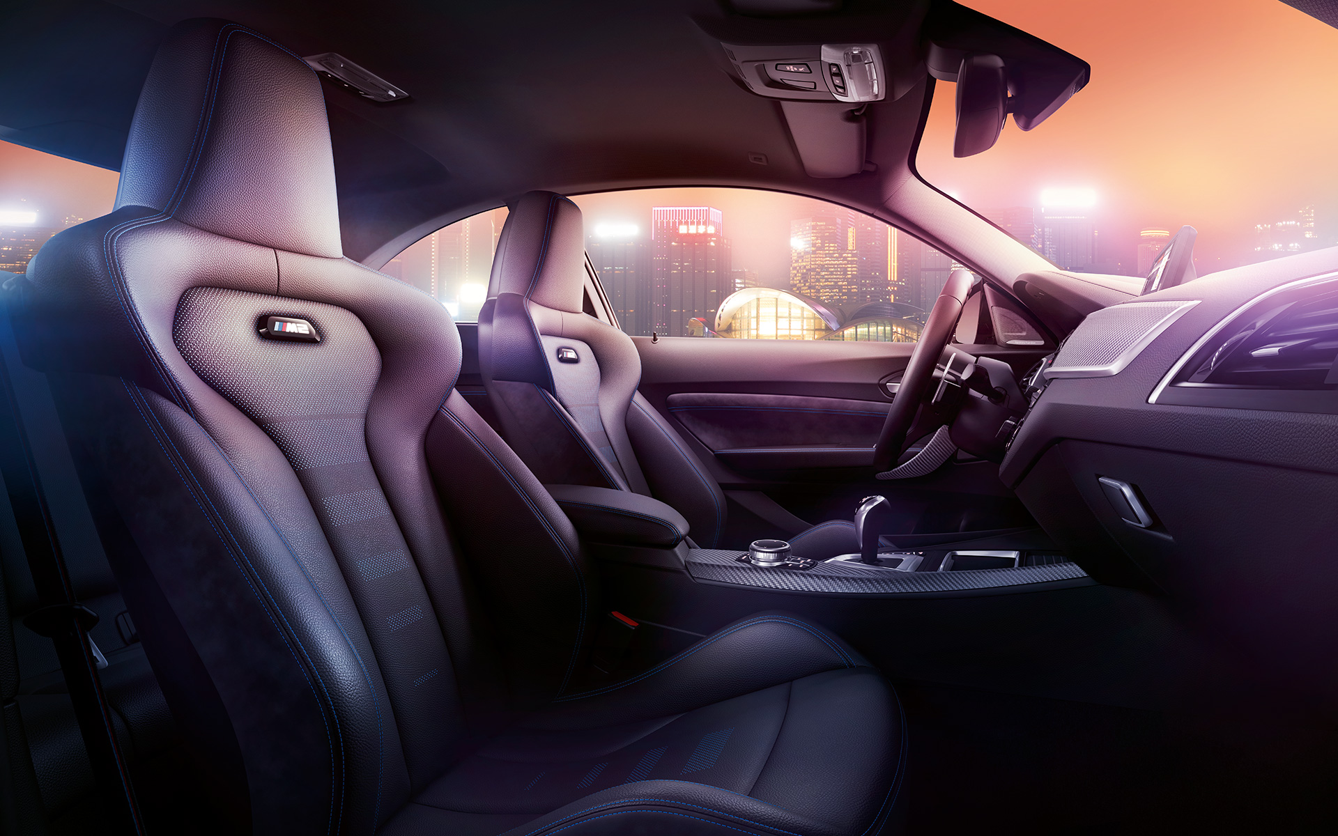 BMW M2 Competition sportovní sedadla Kokpit a M Sport sedadla BMW M2 Competition, mrakodrap nočního města v pozadí.