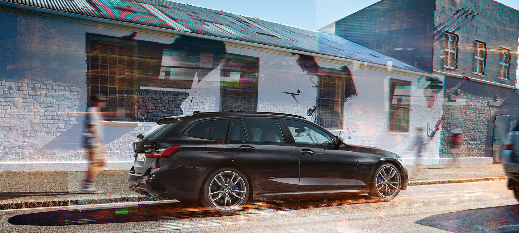 Boční pohled BMW M340i xDrive Touring BMW M340i xDrive Touring G21 v metalické barvě Black Sapphire (černá) na ulici při pohledu z boku