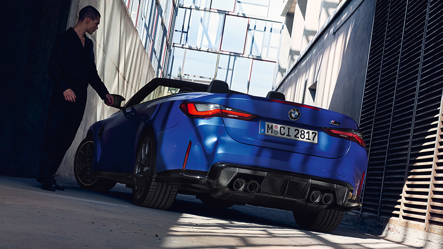 BMW M4 Competition Cabrio s pohonem M xDrive G83 2021 ze tříčtvrtečního pohledu zezadu BMW M4 Competition Cabrio s pohonem M xDrive G83 2021 v metalické Frozen Portimao Blue (modrá) ze tříčtvrtečního pohledu zepředu s mužem