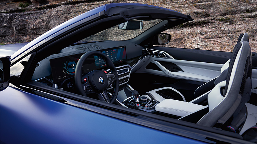 BMW M4 Competition Cabrio s pohonem M xDrive G83 2021 interiér se staženou střechou BMW M4 Competition Cabrio s pohonem M xDrive G83 2021 metalický lak Individual Frozen Portimao Blue (modrá) kokpit a interiér se staženou plátěnou střechou