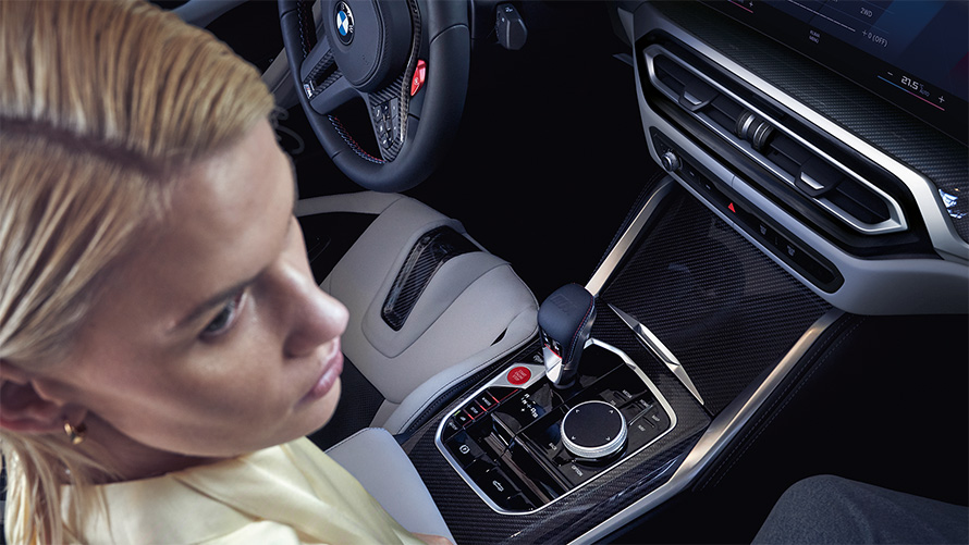 BMW M4 Competition Cabrio s pohonem M xDrive G83 interiér 2021 středová konzola BMW M4 Competition Cabrio s pohonem M xDrive G83 2021 středová konzola s ženou na sedadle spolujezdce